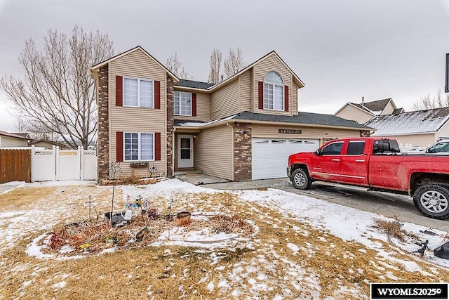 traditional-style house with concrete driveway, brick siding, fence, and an attached garage