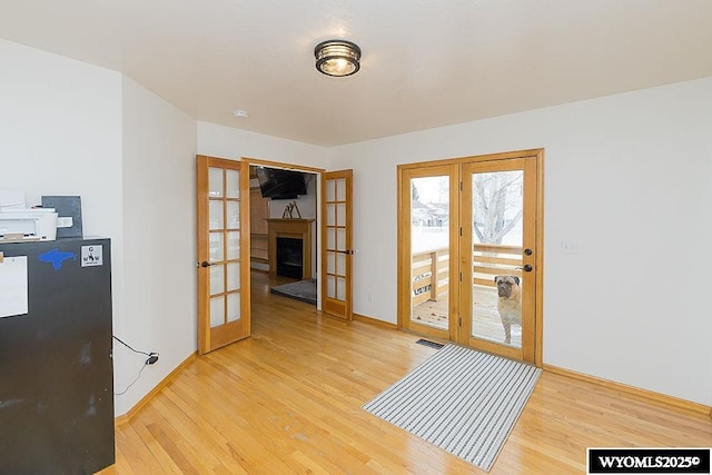 doorway with light wood-style floors, visible vents, baseboards, and french doors