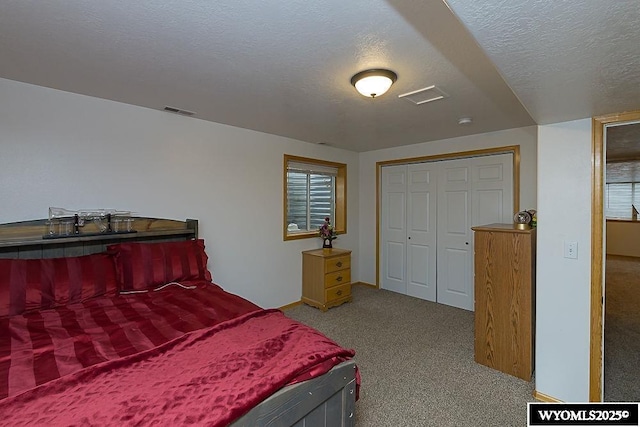 bedroom with a closet, carpet flooring, visible vents, and a textured ceiling