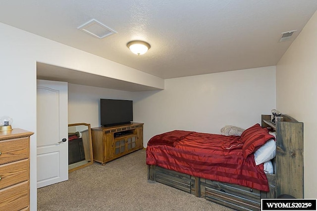 bedroom with carpet, visible vents, and a textured ceiling