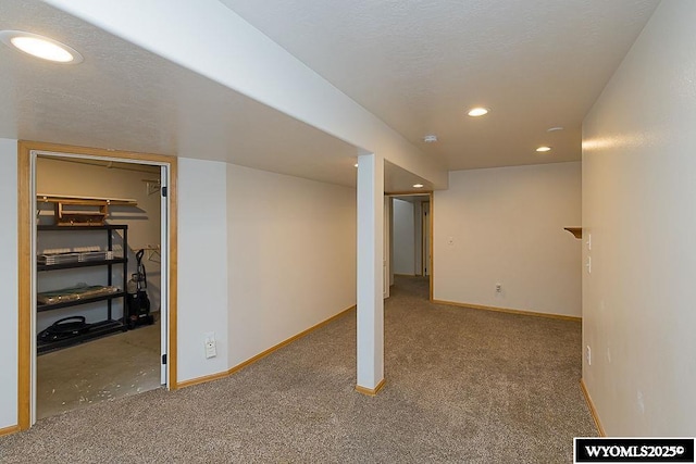 finished below grade area with a textured ceiling, baseboards, carpet flooring, and recessed lighting