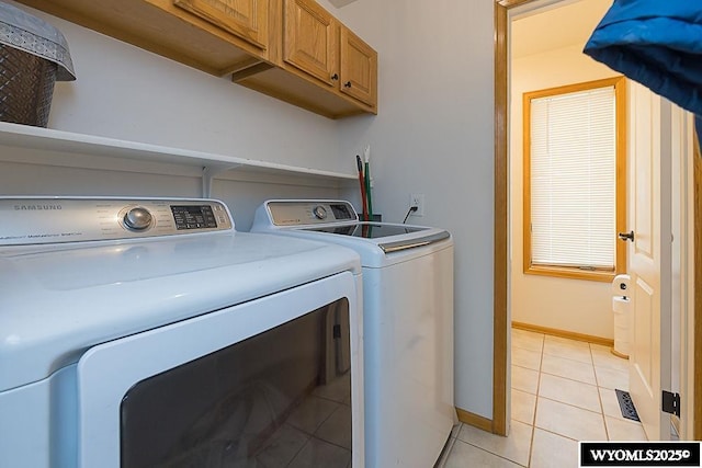 laundry room featuring separate washer and dryer, light tile patterned flooring, cabinet space, and baseboards