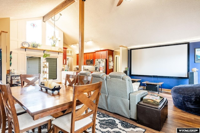 dining area with a textured ceiling, high vaulted ceiling, beam ceiling, and wood finished floors