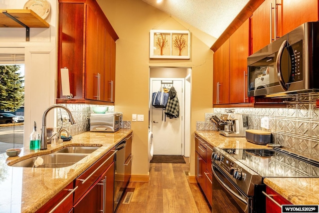 kitchen featuring dark brown cabinets, appliances with stainless steel finishes, light wood-type flooring, and a sink