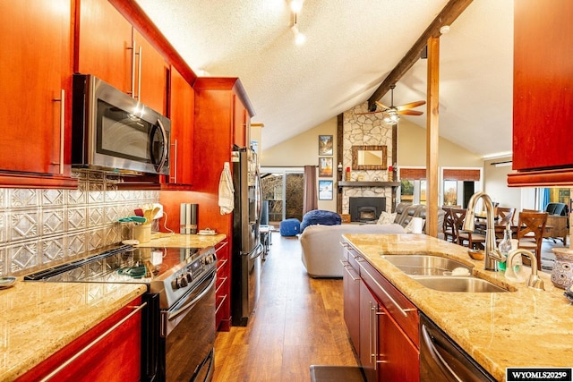 kitchen featuring appliances with stainless steel finishes, open floor plan, wood finished floors, dark brown cabinets, and a sink