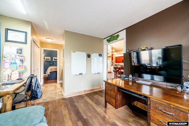 office area featuring a textured ceiling, baseboards, and wood finished floors