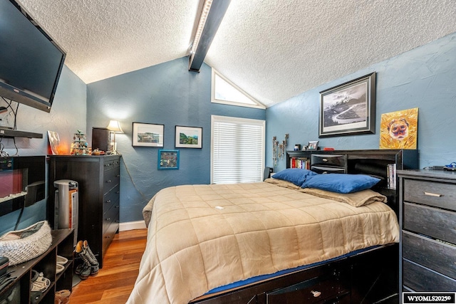 bedroom featuring a textured wall, vaulted ceiling with beams, a textured ceiling, and wood finished floors