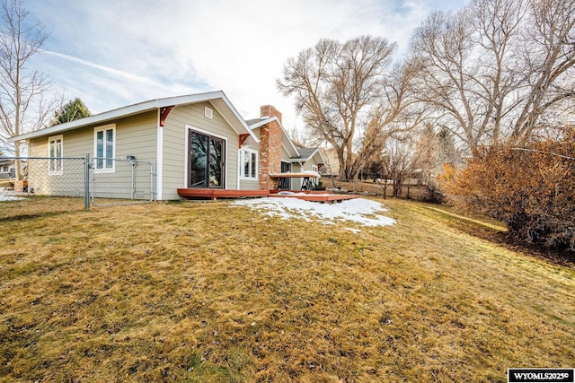 view of side of property with a wooden deck, a chimney, fence, and a yard