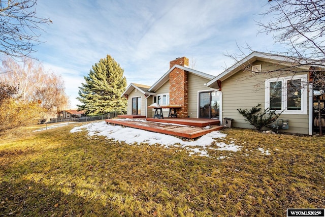 snow covered back of property featuring a yard, a chimney, fence, and a wooden deck