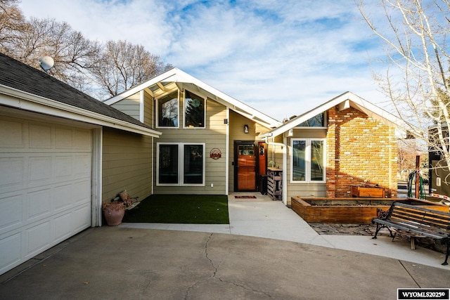 mid-century inspired home featuring driveway, an attached garage, and brick siding