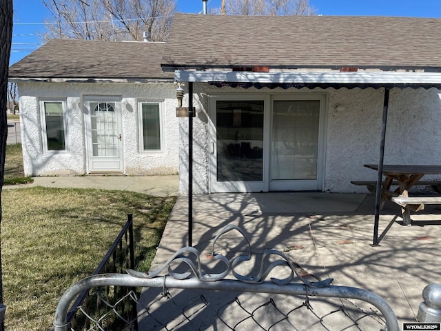 back of house featuring a shingled roof, a patio area, and stucco siding