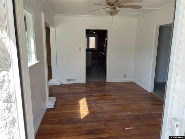 unfurnished room featuring ornamental molding, a ceiling fan, visible vents, and wood finished floors