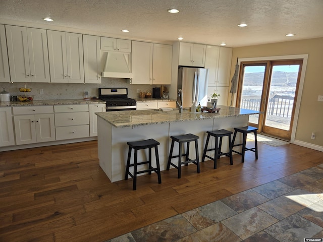 kitchen with premium range hood, appliances with stainless steel finishes, a kitchen island, and white cabinetry