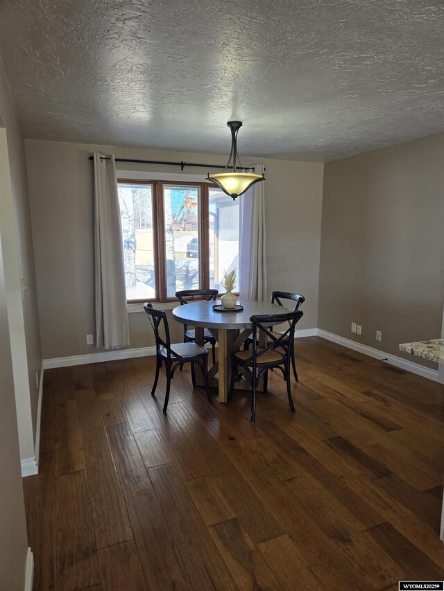 dining space featuring dark wood-style floors, baseboards, and a textured ceiling