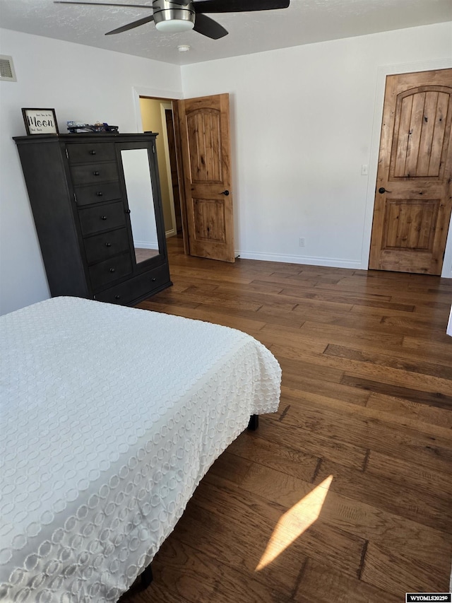 bedroom featuring a ceiling fan, wood finished floors, visible vents, and baseboards
