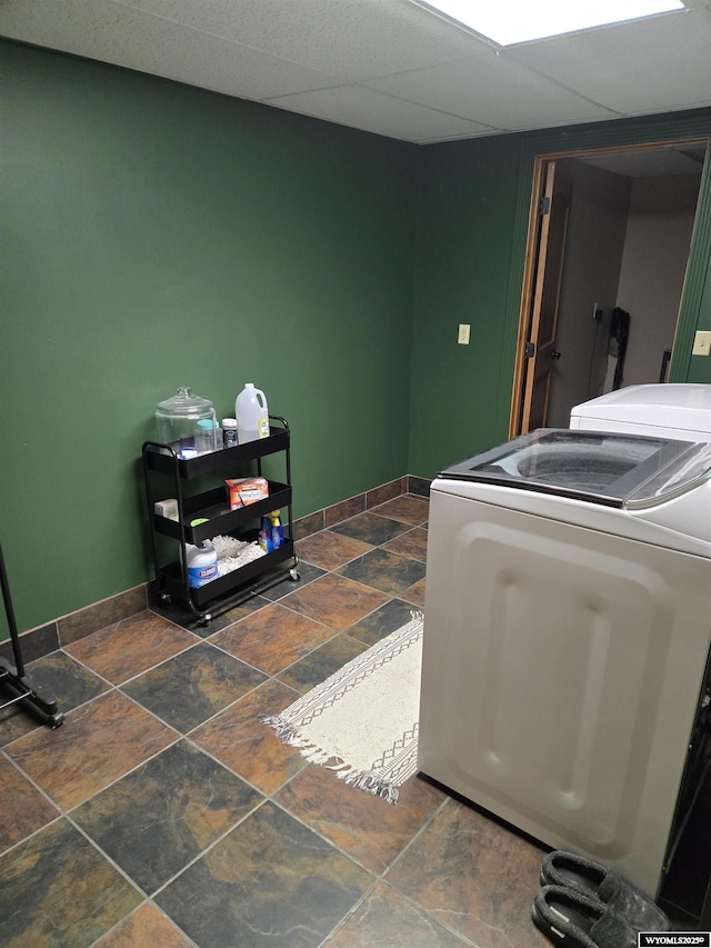 clothes washing area with laundry area, baseboards, stone tile floors, and separate washer and dryer