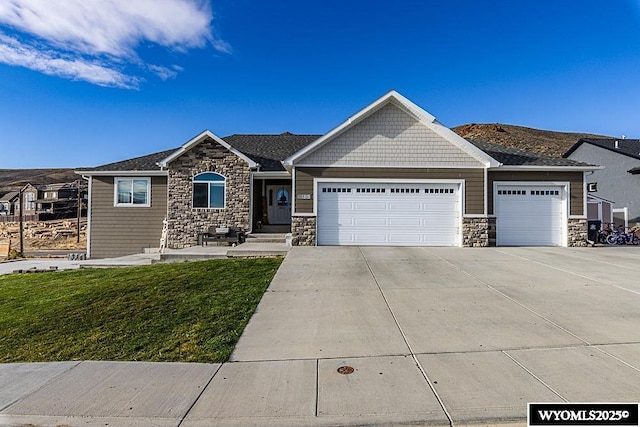 view of front facade with a front lawn, stone siding, driveway, and an attached garage