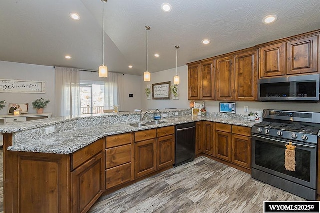 kitchen with a peninsula, appliances with stainless steel finishes, a sink, and light stone countertops