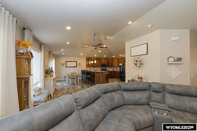 living room featuring lofted ceiling, a textured ceiling, recessed lighting, and wood finished floors