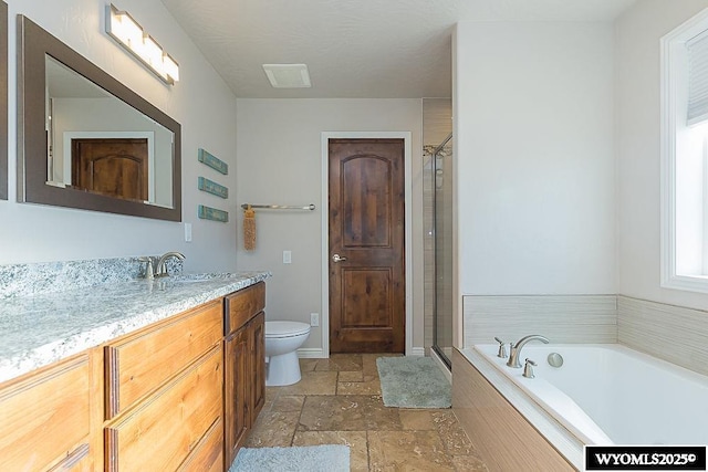 bathroom with a garden tub, a shower stall, stone tile flooring, and vanity