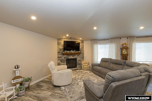 living room featuring a textured ceiling, a fireplace, vaulted ceiling, and wood finished floors