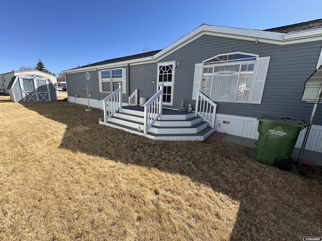 rear view of property featuring an outbuilding, a storage shed, and a lawn