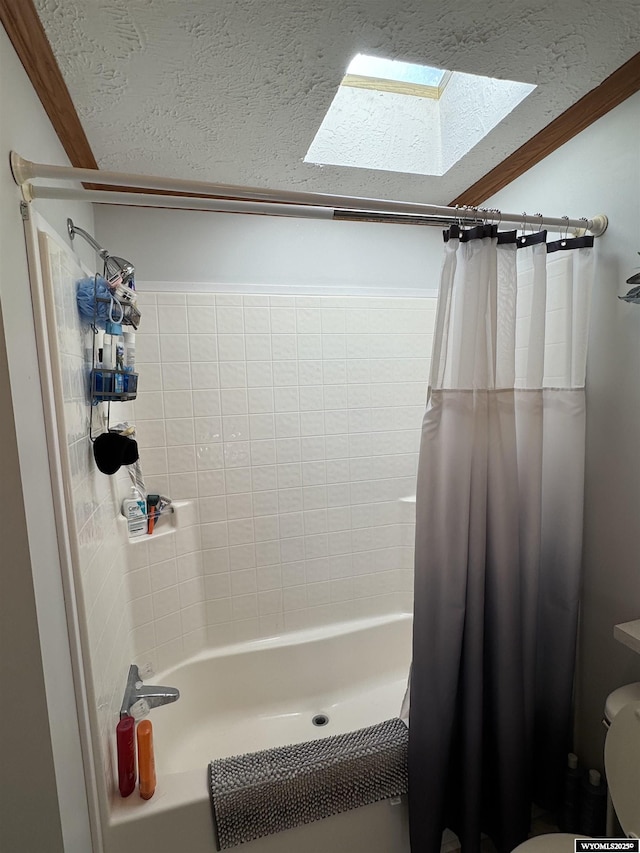 bathroom featuring a textured ceiling, a skylight, shower / bath combo with shower curtain, and toilet