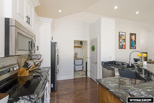 kitchen featuring dark wood-style flooring, stainless steel appliances, white cabinetry, a sink, and dark stone counters