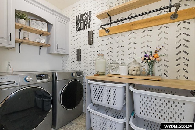 laundry area featuring washing machine and clothes dryer, cabinet space, and wallpapered walls