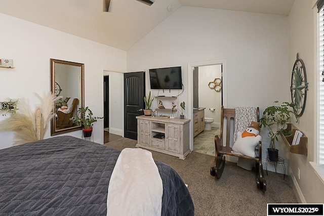 bedroom featuring high vaulted ceiling, dark colored carpet, baseboards, and ensuite bath