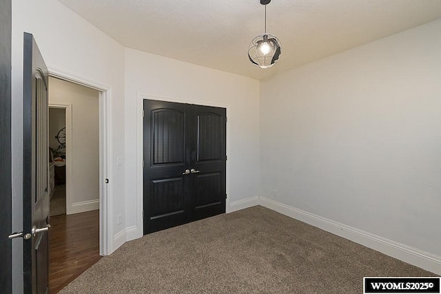 unfurnished bedroom with dark colored carpet and baseboards