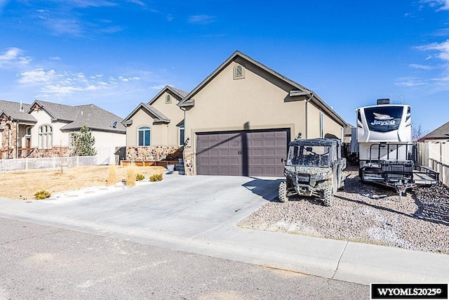 view of front of house featuring an attached garage, driveway, fence, and stucco siding