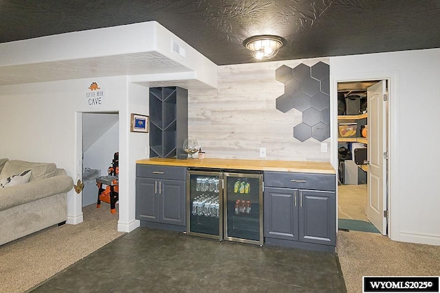 bar featuring a textured ceiling, wine cooler, visible vents, dark colored carpet, and a bar