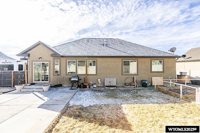 back of property with a shingled roof, a patio area, fence, and stucco siding