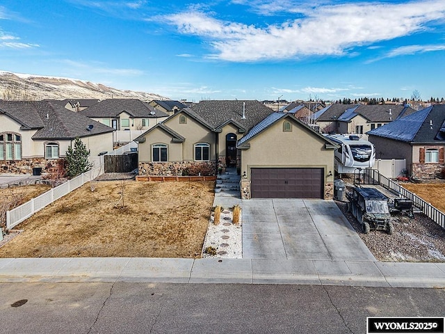 french country home featuring stucco siding, fence, a garage, a residential view, and driveway