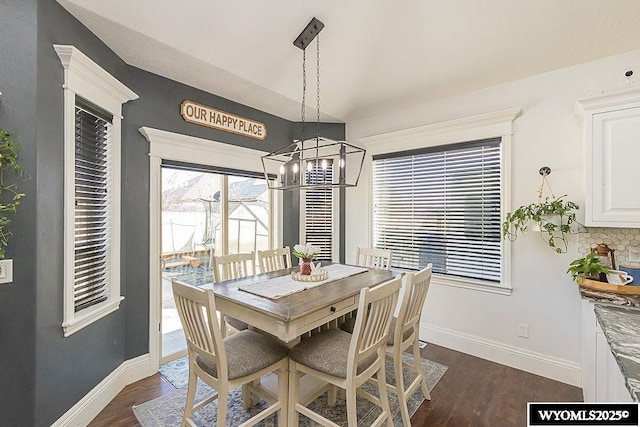 dining space featuring a notable chandelier, dark wood-type flooring, and baseboards