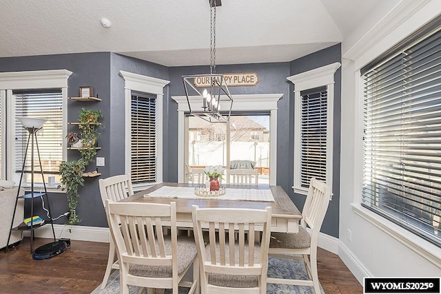 dining room with a chandelier, a textured ceiling, wood finished floors, and baseboards