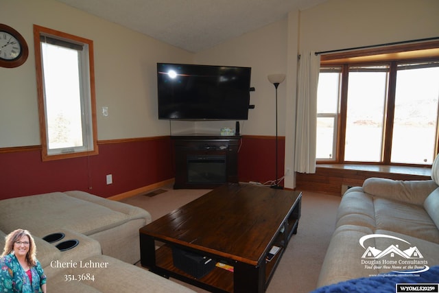 living area with carpet floors, plenty of natural light, visible vents, and vaulted ceiling