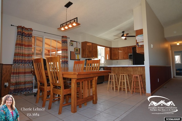 dining room featuring light tile patterned floors, ceiling fan, a textured ceiling, and wainscoting