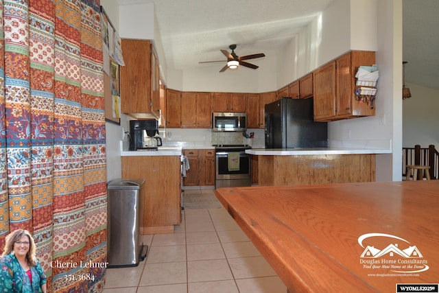 kitchen featuring light tile patterned floors, ceiling fan, stainless steel appliances, light countertops, and brown cabinets