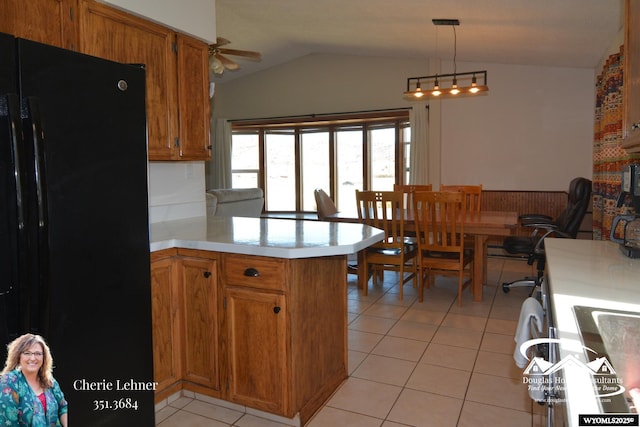 kitchen featuring light tile patterned floors, lofted ceiling, light countertops, freestanding refrigerator, and a peninsula