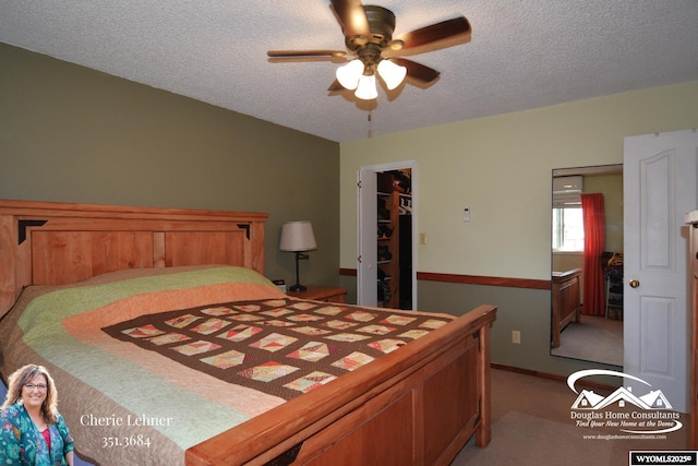 bedroom with a ceiling fan, light colored carpet, a walk in closet, a textured ceiling, and a closet