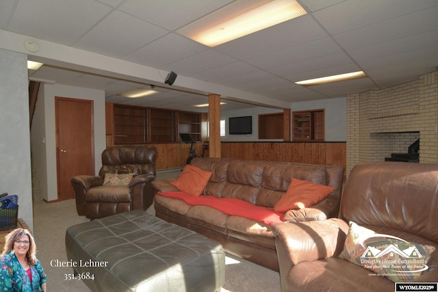 carpeted living area featuring a paneled ceiling and wood walls