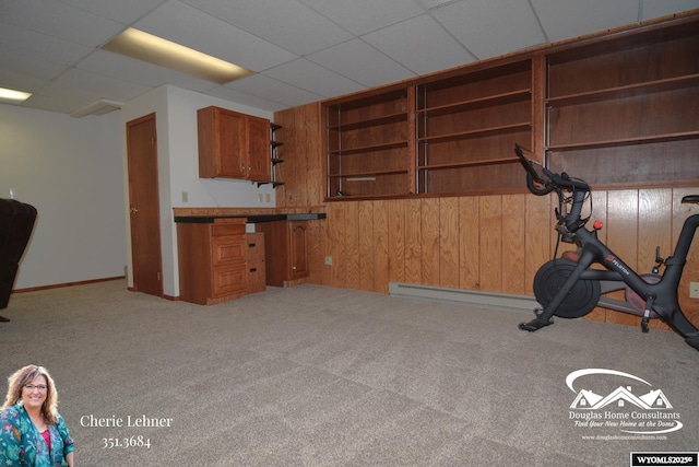 workout area with carpet, a drop ceiling, and wood walls