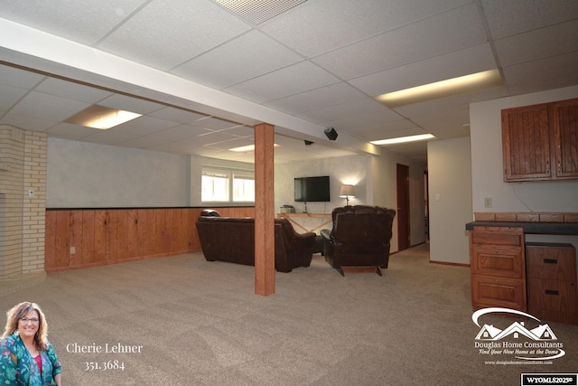 interior space featuring a wainscoted wall, a drop ceiling, visible vents, and light colored carpet