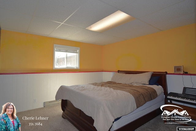 bedroom featuring carpet floors, a wainscoted wall, a drop ceiling, and baseboard heating