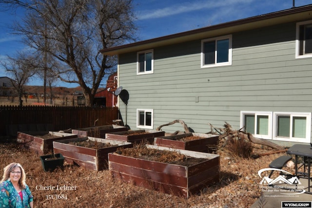 view of side of home with fence and a vegetable garden