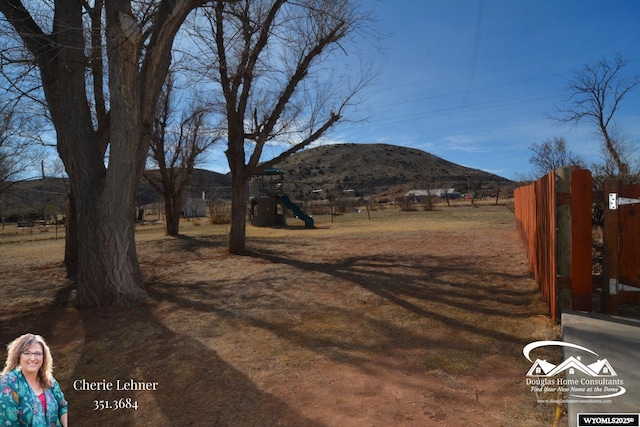 view of yard featuring playground community, fence, and a mountain view