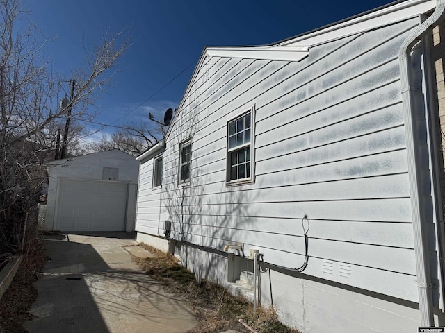 view of property exterior with an outbuilding, a detached garage, and driveway