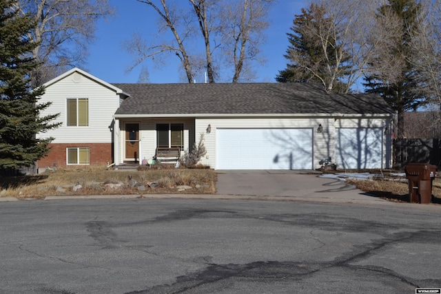 split level home with an attached garage, roof with shingles, concrete driveway, and brick siding